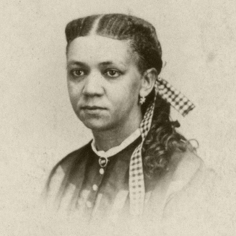 Black and white headshot photo of Fanny Jackson Coppin with hair braided with gingham ribbon while also wearing a button up blouse