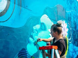 Female mural artist creating art on the wall